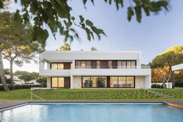 Casa moderna con piscina y jardines en Valencia, destacando su diseño arquitectónico minimalista y elegante, rodeada de árboles y vegetación.