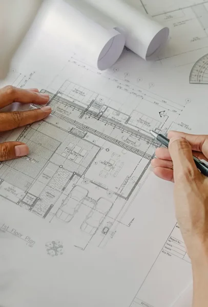 Plano de arquitectura en ZARAGOZA, mostrando los detalles de una planta baja, con una persona revisando el diseño con un bolígrafo.