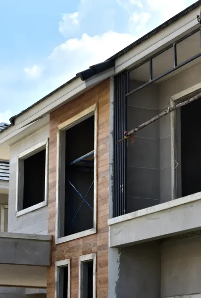 Construcción en proceso en Valencia, mostrando las fachadas de una casa con detalles de ventanas sin terminar y trabajos en curso.