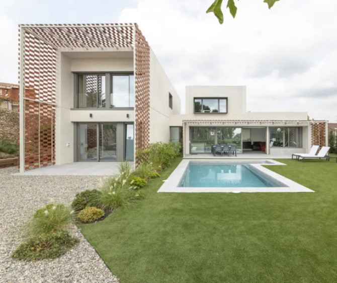 Casa modular con grandes ventanales conectada con el jardín, la terraza y la piscina